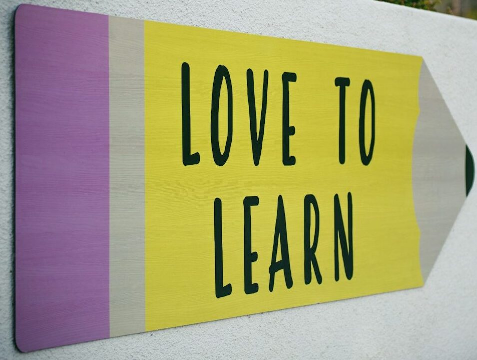 love to learn pencil signage on wall near walking man